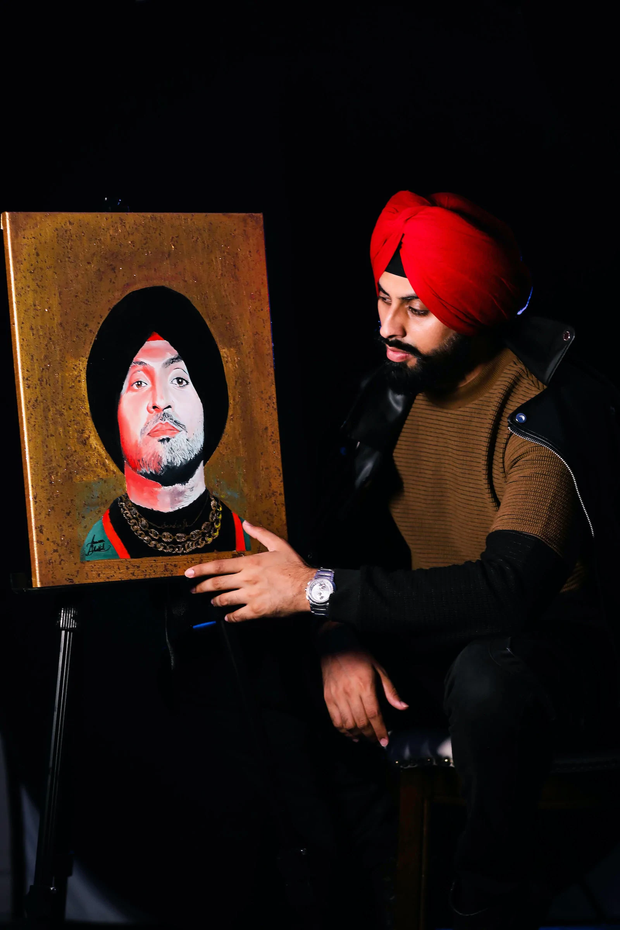 Diljit Dosanjh holding his hand-painted portrait by Armaan Bhattal